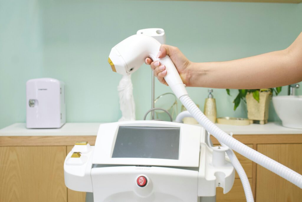 Close-up of a hand holding a laser hair removal device in a clinic setting.